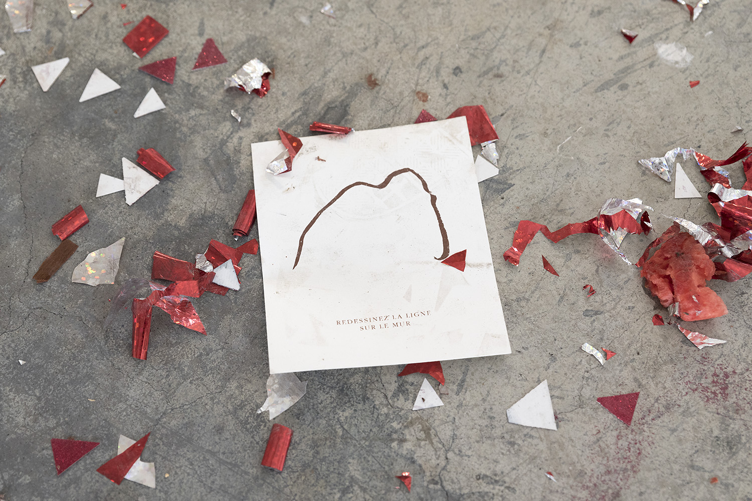 une feuille de dessin de mammouth est au sal au milieu des paillettes et cotillons, on peut voir des traces de pas sur le dessin.